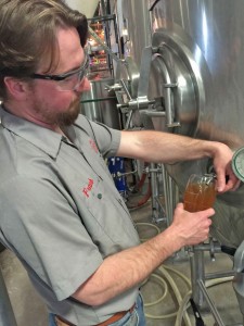 Franklin pulls a pint from the fermenting tank
